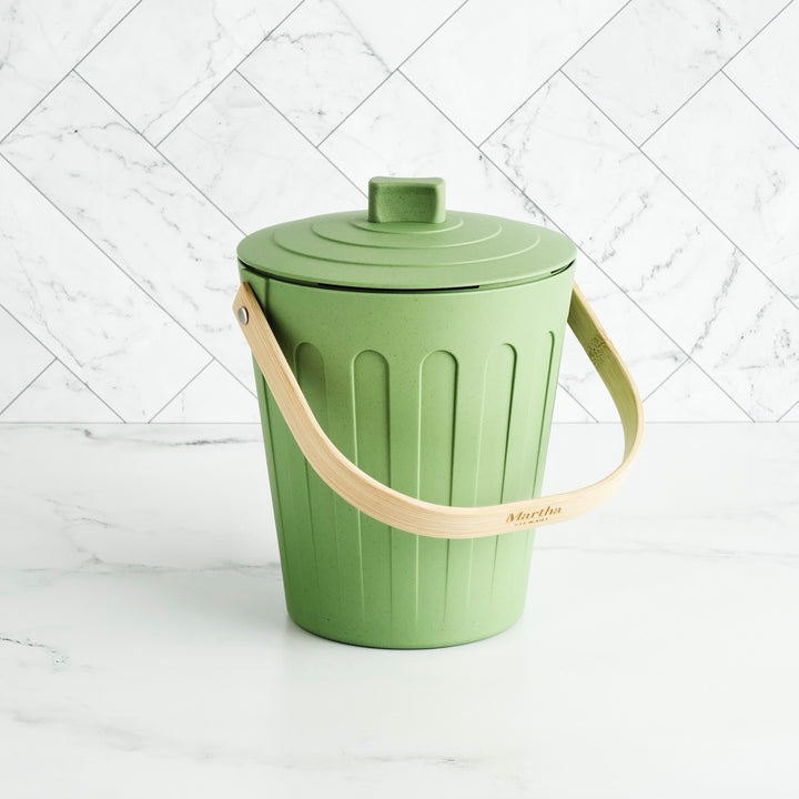 Green trash bin with a beige handle on a white background